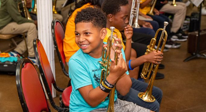 kid holding trumpet smiling
